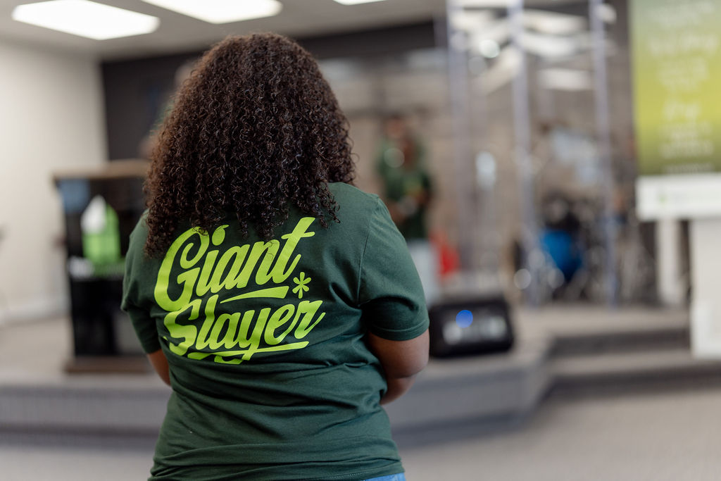 A woman in a Giant Slayer shirt facing the platform during a service