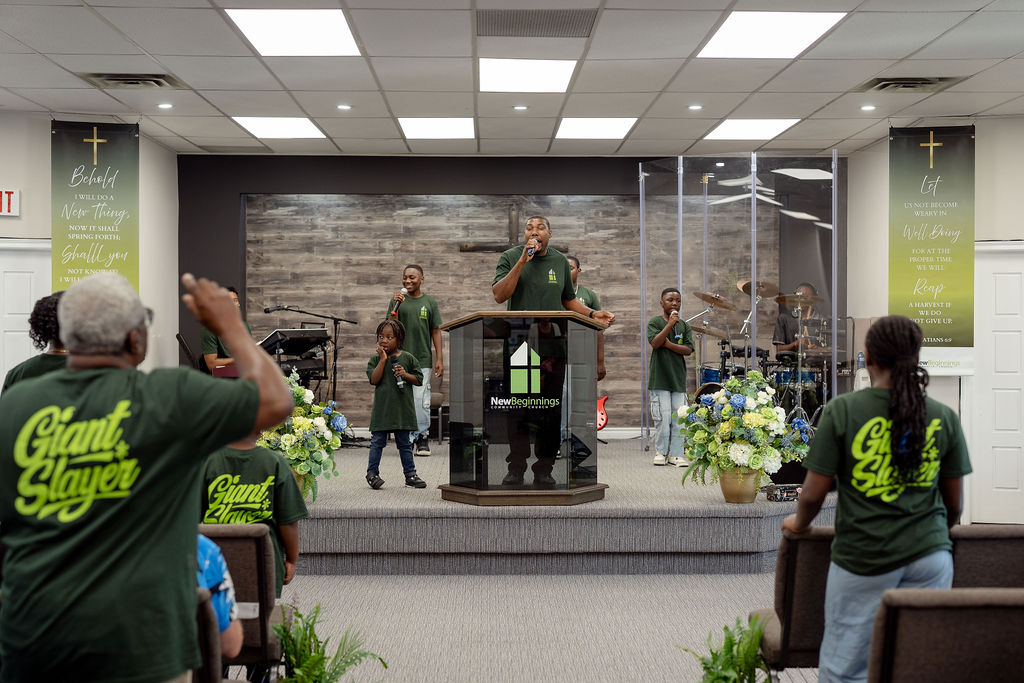 Children and adults singing into microphones on the platform during a service